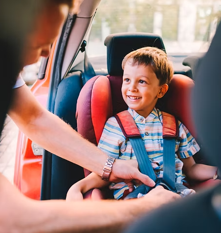 Father buckling child into car seat